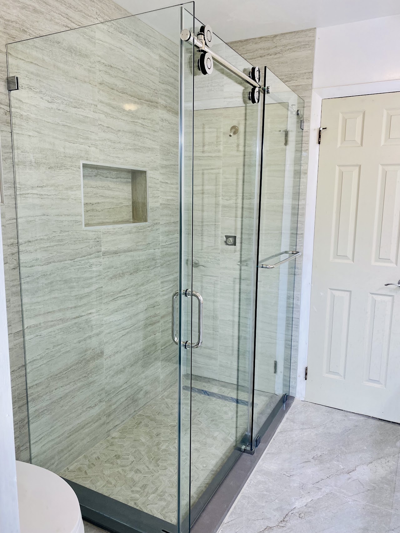 Glass shower enclosure with light tile