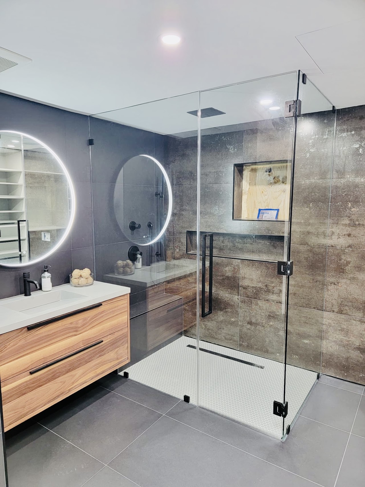 Bathroom with round illuminated mirror and glass shower